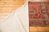 Reverse side of the antique Anatolian runner with white backing, showing bold red and natural dye accents.