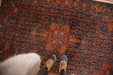 Farahan Sarouk rug's intricate brick red medallion and navy blue henna plant field.