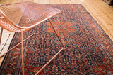 Intricate brick red and navy henna plant designs on a vintage Farahan Sarouk rug.