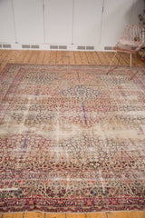 Antique Kerman carpet: cochineal red millefleur panels with scalloped contours and navy border.