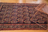 Intricate patterns of geometric figures and floral botehs on a navy Malayer rug.