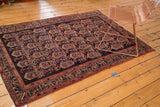 Repeating floral botehs and geometric borders on the dark navy indigo Malayer rug.