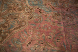 Vintage Persian rug detail: blush raspberry floral field with dark blue, brown, and visible seam.