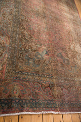Meshed carpet corner: intricate floral border, blush field, dark teal accents, and fringe.