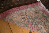 Hand-knotted back of a vintage Meshed rug with secured raspberry edge and faded motifs.