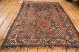 Vintage Qashqai rug corner, showing geometric border patterns, madder red, and tattered fringe.