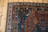 Vintage Qashqai rug corner, madder red and blue field with whimsical motifs and patch.