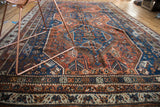 Textured field and border of the Qashqai rug in madder root red and deep blue.