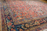 Geometric floral patterns on the blush field and navy border of a Heriz rug.