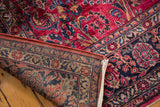 Hand-knotted vintage American Sarouk rug corner revealing foundation and raspberry floral motifs.