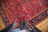 Vintage Mehrivan Heriz carpet's faded cherry red field, geometric blossoming flowers, and dark navy border.