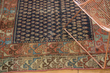 Visible wear on the navy boteh field and ornate geometric border of an antique Hamadan rug.