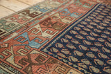 Antique Hamadan rug's madder red geometric border, textured pile, and navy blue boteh field pattern.