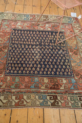 Close-up of antique Hamadan rug's traditional scrolling borders and navy boteh field.
