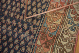 Antique Hamadan rug detail: navy field with oxidized green boteh, visible wear; geometric red border.