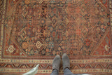 Antique Qashqai rug's dense allover field with tribal animals, plants, in madder, navy, and camel.