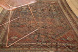 Antique Qashqai rug field: germinating plants, pinwheels, madder red, navy, camel, showing even wear.