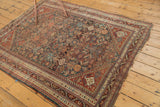Antique Qashqai rug right corner: geometric border, dark teal field, and tattered side.