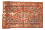 Distressed Antique Fereghan rug, red diamond medallion, blue spandrels, detailed floral motifs, and aged, even wear.
