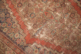 Worn madder red field and time-softened floral motifs with aged patina on an antique Fereghan rug.
