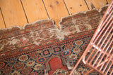 Tattered edge of the distressed Antique Fereghan rug, with visible splits and rich patina.