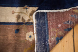 Folded vintage Chinese Peking carpet showcasing hand knotting on reverse, with cobalt blue and cream floral patterns.