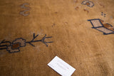 Stylized arts and crafts pattern details on the tea brown pile of a vintage Peking carpet.