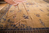 Dark navy geometric border, stylized motifs, and visible wear on a vintage Peking carpet.