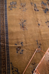 Vintage Peking carpet detail: dark navy Greek key border, golden brown field, wear revealing white knots.
