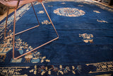 Vintage Chinese Peking rug detail: ornate floral vases, branches, and geometric border on cobalt field.