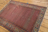 Vintage Hamadan rug corner with repeating mir design, madder red field and blue geometric borders.