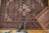 Detail of the vintage Dargezine rug's expressive blossoming floral medallion with a navy Herati motif field.