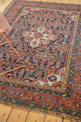 Vintage Dargezine rug's lower right corner showing brick red border, navy field, and stylized Herati motifs with even wear.