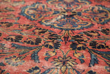 Detail of vintage Lilihan rug with distressed floral pattern in raspberry, blue, and gold.