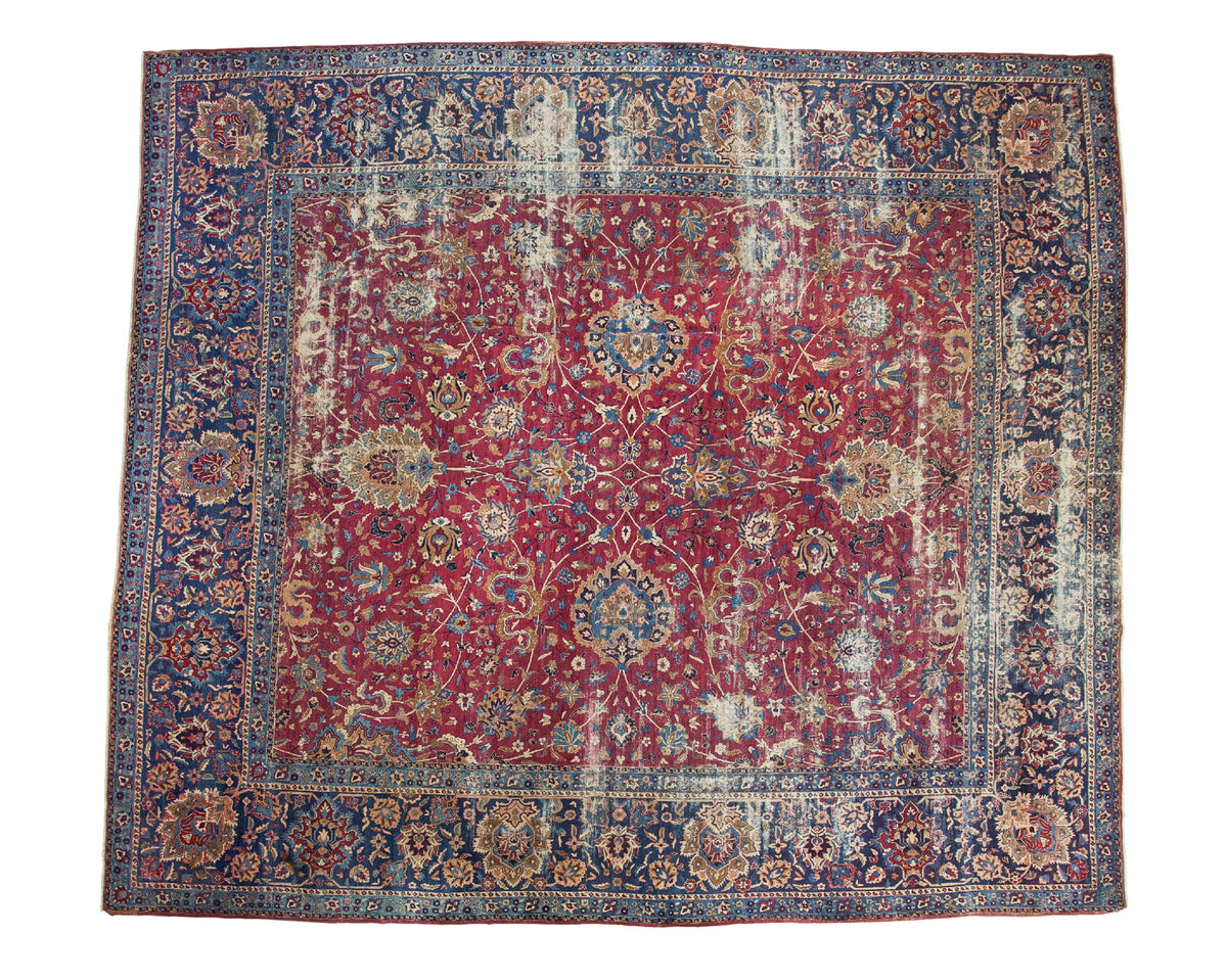 Antique Yezd carpet: distressed cochineal red field with sprawling palmettes and navy border.