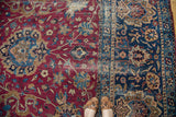 Professional seam joining cochineal red and navy floral fields of antique Persian Yezd rug.