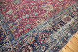 Antique Yezd carpet corner detail with rich cochineal red field, navy border, and aged floral palmettes.