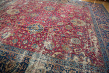 Antique Yezd carpet with aged patina across its cochineal red field and navy border.
