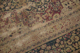 Distressed vintage Meshed carpet showing faded floral motifs and muted wine red, navy, ivory.