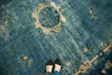 Watery blue antique Peking carpet showing an ivory floral roundel, eucalyptus leaves, and patina.