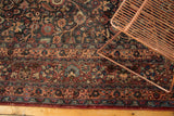 Close-up of a Meshed carpet's intricate border showing distressed floral vine motifs.