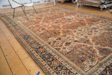 Corner detail of the vintage Mahal rug featuring terra cotta scrolling vinery and navy blue border.