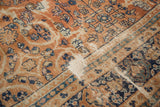 Vintage Mahal carpet detail with terracotta field, navy blue scrolling vinery, and worn texture.