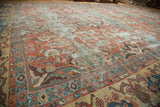 Intricate terra cotta and blue sprawling patterns with visible wear on an antique Sultanabad carpet.