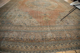 Distressed field and patterned borders of an antique Jalili Tabriz rug in apricot, blue, and ivory tones.