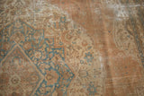 Antique Tabriz rug's distressed pile reveals pale apricot, ivory, and sky blue curvilinear motifs.