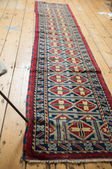 Afghan runner's geometric medallion motif in indigo blue, cherry red, and saffron yellow.