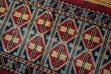 Hand-knotted Afghan rug detail: double column of red, saffron, and indigo medallions.