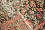Distressed vintage Malayer rug runner corner with tattered fringe and visible hand-knotted foundation.