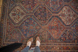 Qashqai rug's geometric repeating panels with animal and plant motifs in red, blue, and gold.